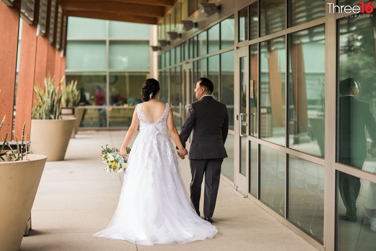 Newly married couple go for a walk holding hands at the Fullerton Community Center wedding venue