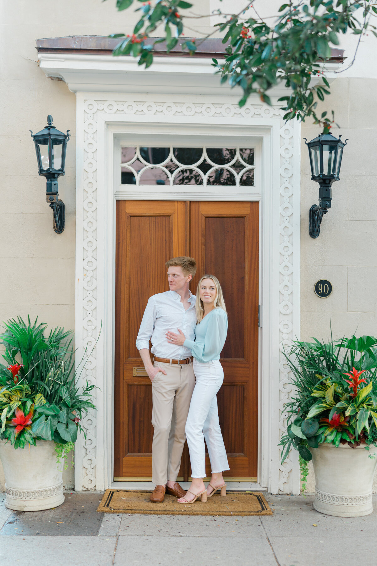 Charleston engagement session with a tropical feel.  Destination engagement photos in downtown Charleston. Gas lantern and big wooden door with touches of green and flowers. Kailee DiMeglio Photography.