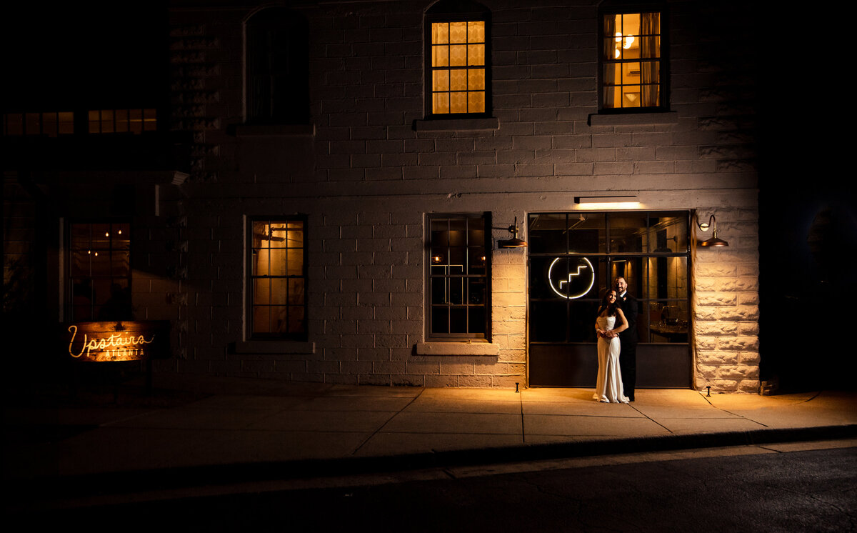 Nighttime-portrait-of-bride-and-groom-outside-Upstairs-Atlanta-highlighting-the-building-and-it's-signage