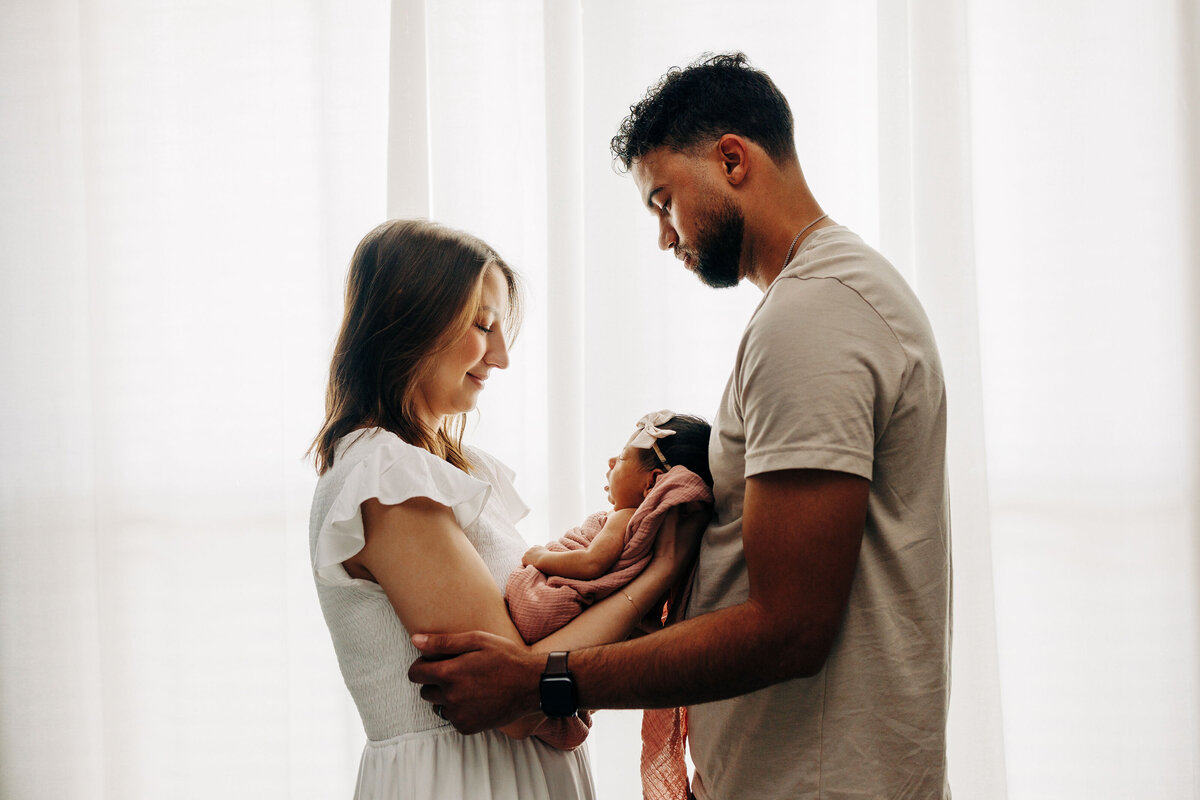 couple holding their baby in between them during a newborn session