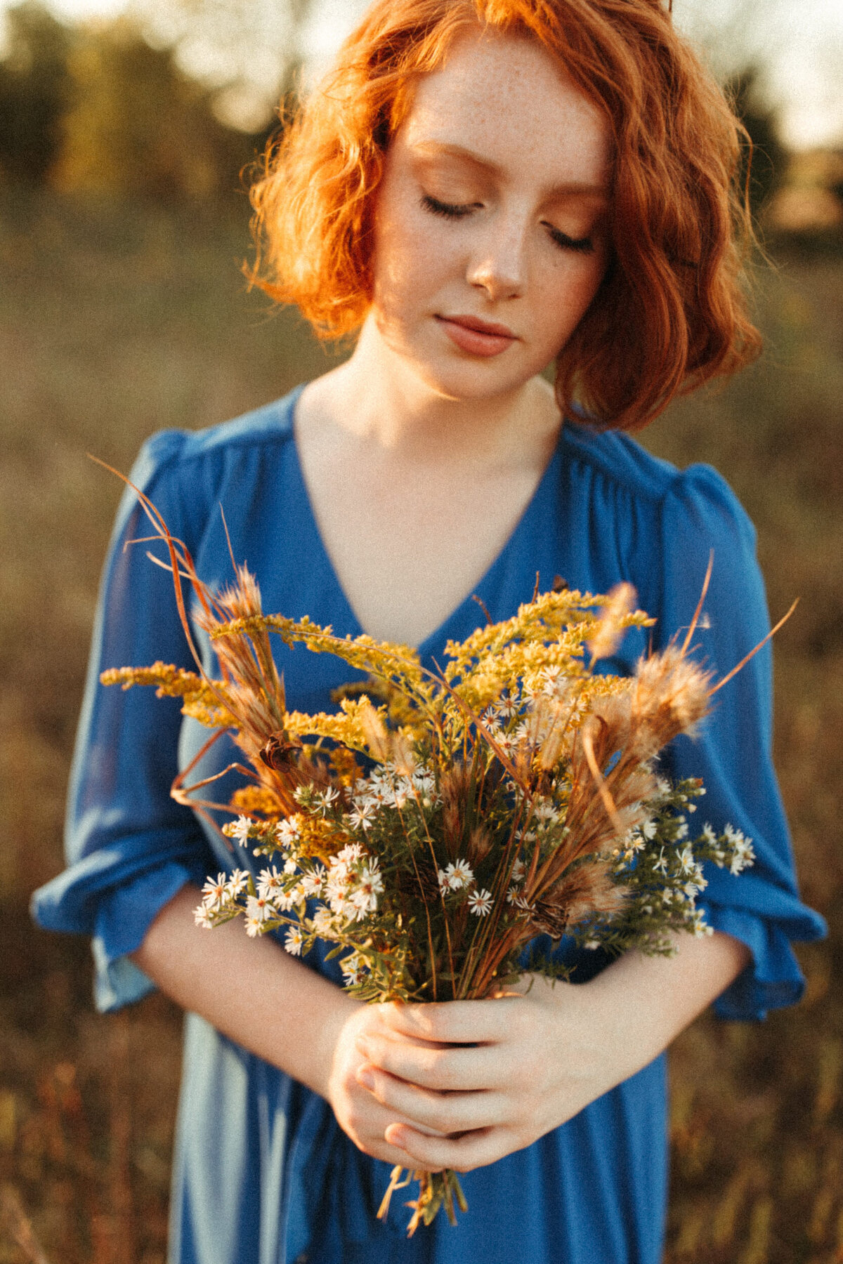 Girl senior holding a bundle of wildflowers she picked from a field during her photoshoot