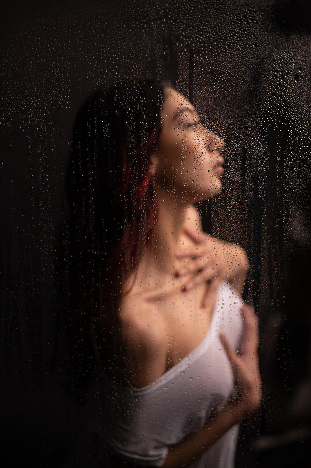 A woman in a sheer white tshirt stands in a steaming shower for her boudoir photo shoot.