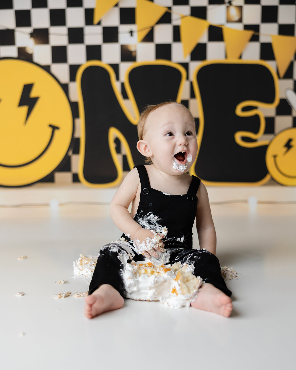 Adorable little one diving into his cake with pure excitement in a bold black-and-yellow themed celebration. Captured by Yucaipa cake smash photographer Kaitlyn Dawn Photography.