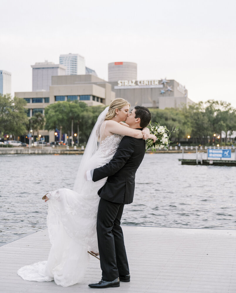 bride and groom kissing on a dock
