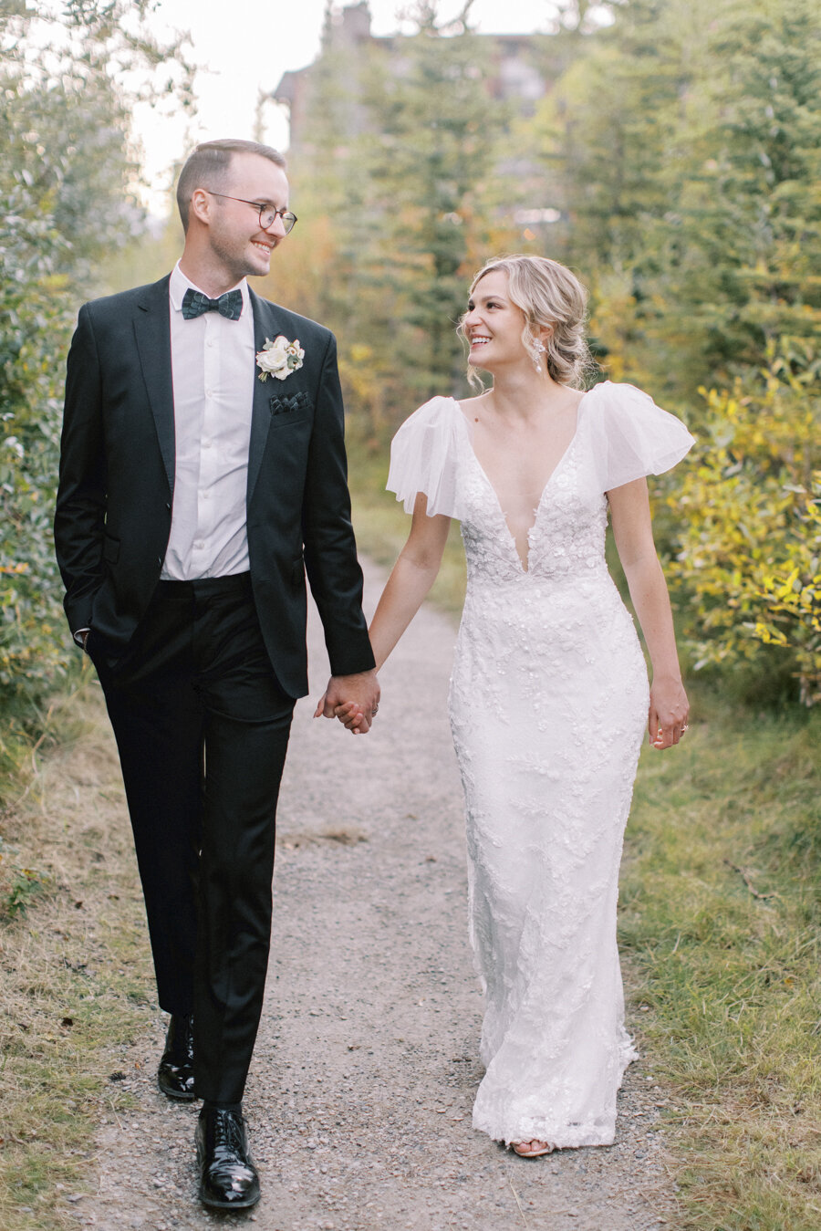 a photograph of a bride and groom holding hands and smiling at each other on their Calgary wedding day