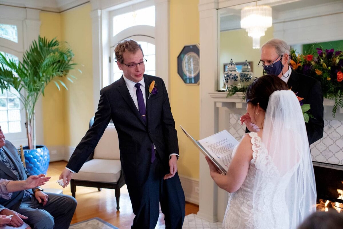 a groom reaches for a tissue to hand to the bride as she reads her wedding vows