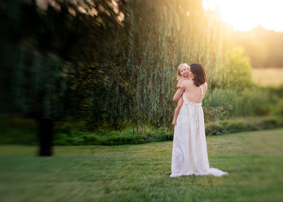 mother in lace dress holding little girl with strong backlight shot with tilt shift lens