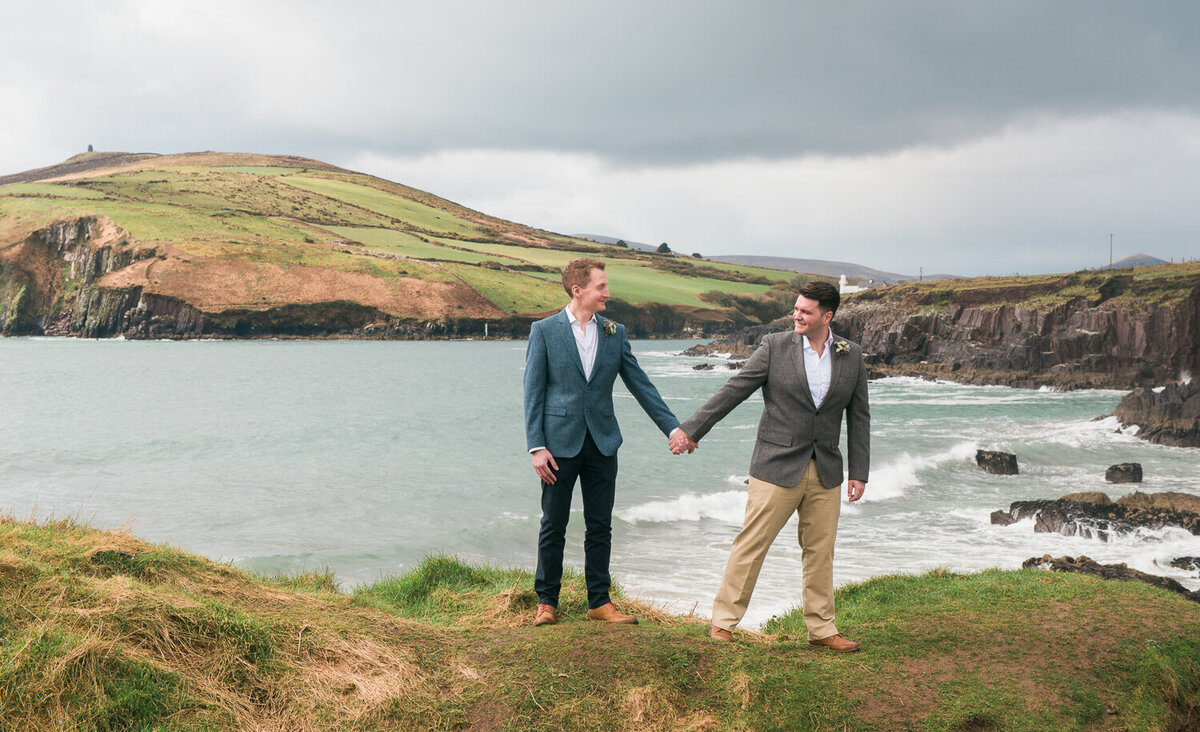 Two grooms standing on cliff overlooking sea in Kerry