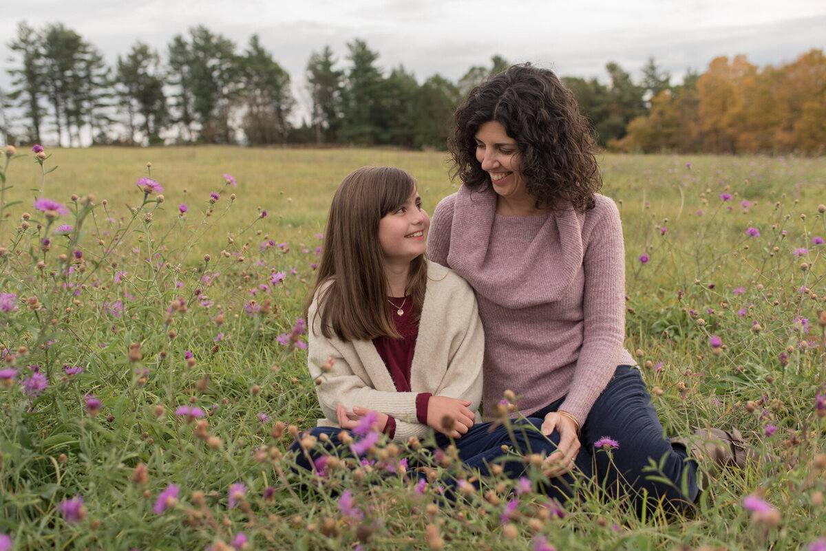 Mother and daughter sitting in field of purple flowers at sunset
