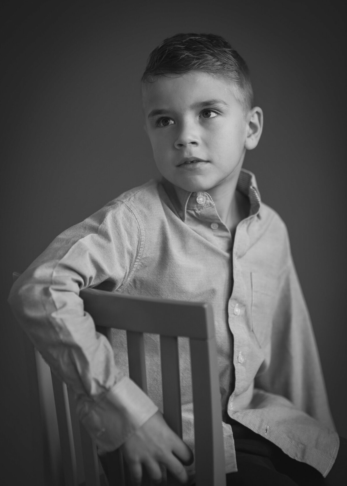 elegant black and white portrait of young boy looking away  wearing a dress shirt