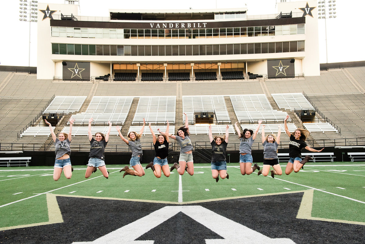 Senior girls on the Vanderbilt football field jumping in the air