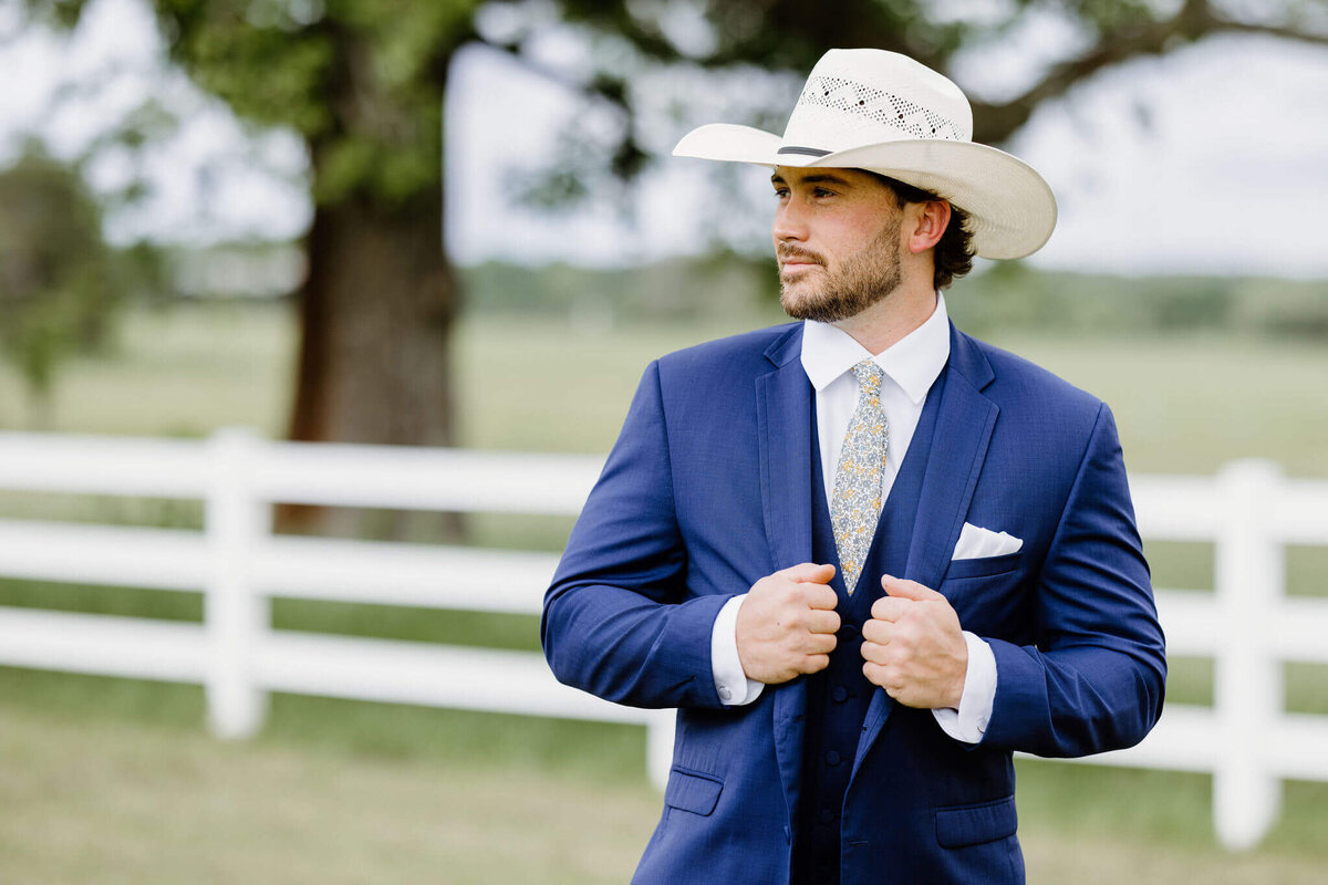 wedding day portrait of groom in navy suit and straw cowboy hat prior to Hallsville, TX wedding day ceremony