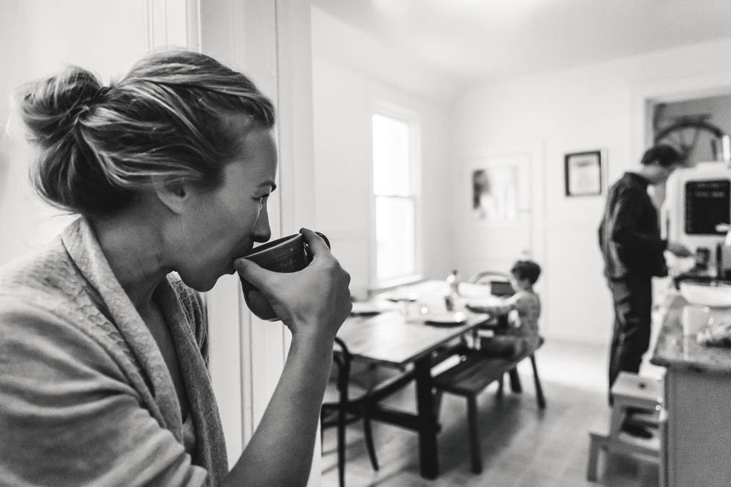 Lifestyle in home family photography session in san francisco apartment mom drinks coffee while watching dad and son