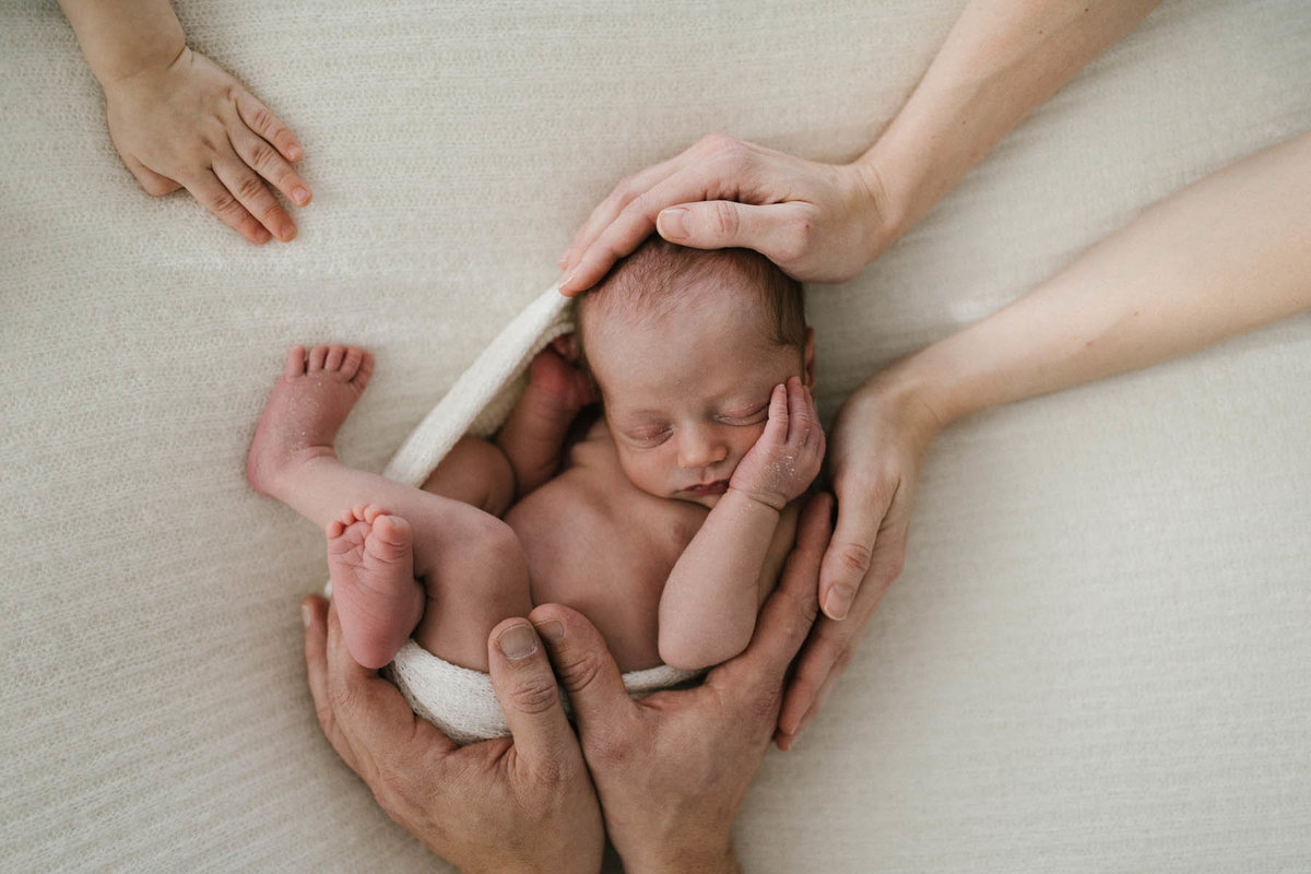 Parents hands on their newborn baby