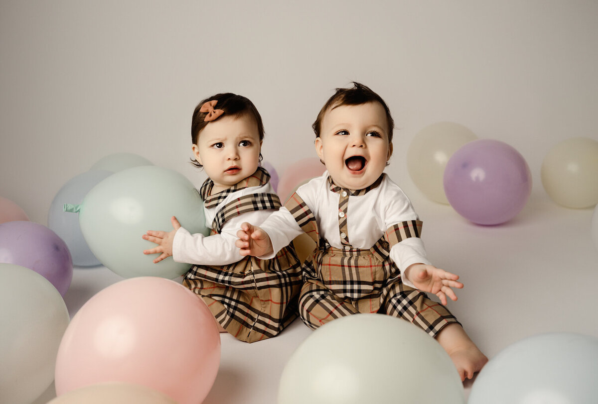 Baby girl and boy twins holding balloons first birthday by for the love of photography Brighton