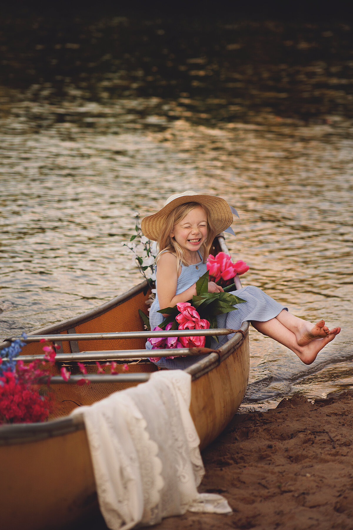 Little girl wearing blue dress and a hat sitting in a canoe during photoshoot in Franklin Tennessee