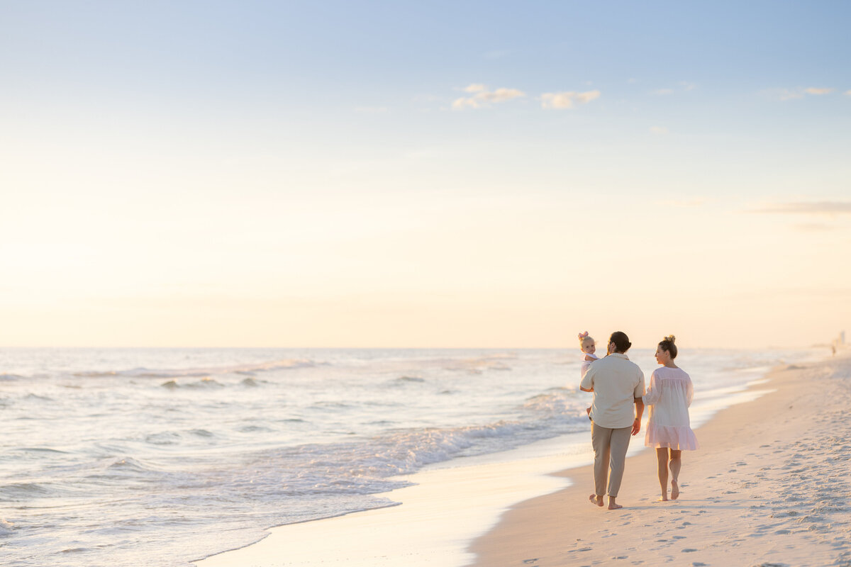 A family of three walking along the beach together