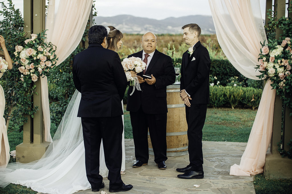 Wedding Photograph Of Three Men in Black Suit And Bride Talking To Each Other Los Angeles