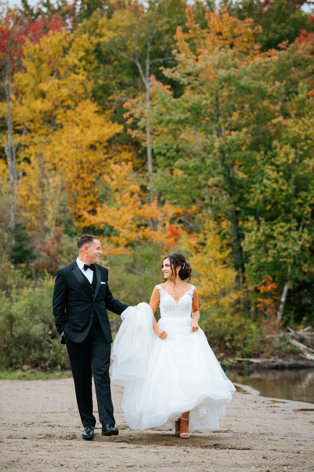 bride and groom walking on beach with foliage at mountain top inn in chittenden vermont