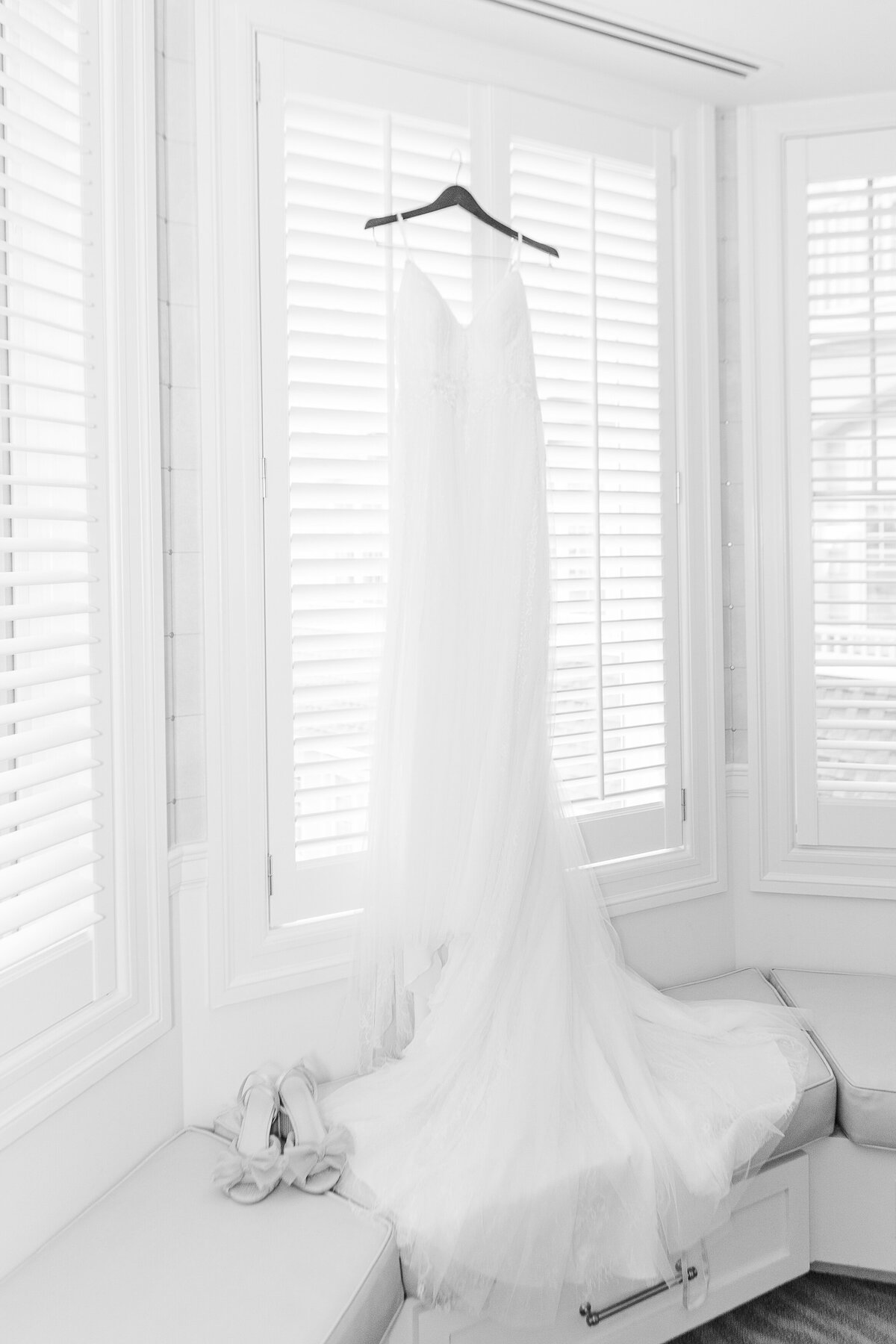Detail image of bride's gown hanging in front of a window at her Madison Beach Hotel wedding. Captured by best New England wedding photographer Lia Rose Weddings.