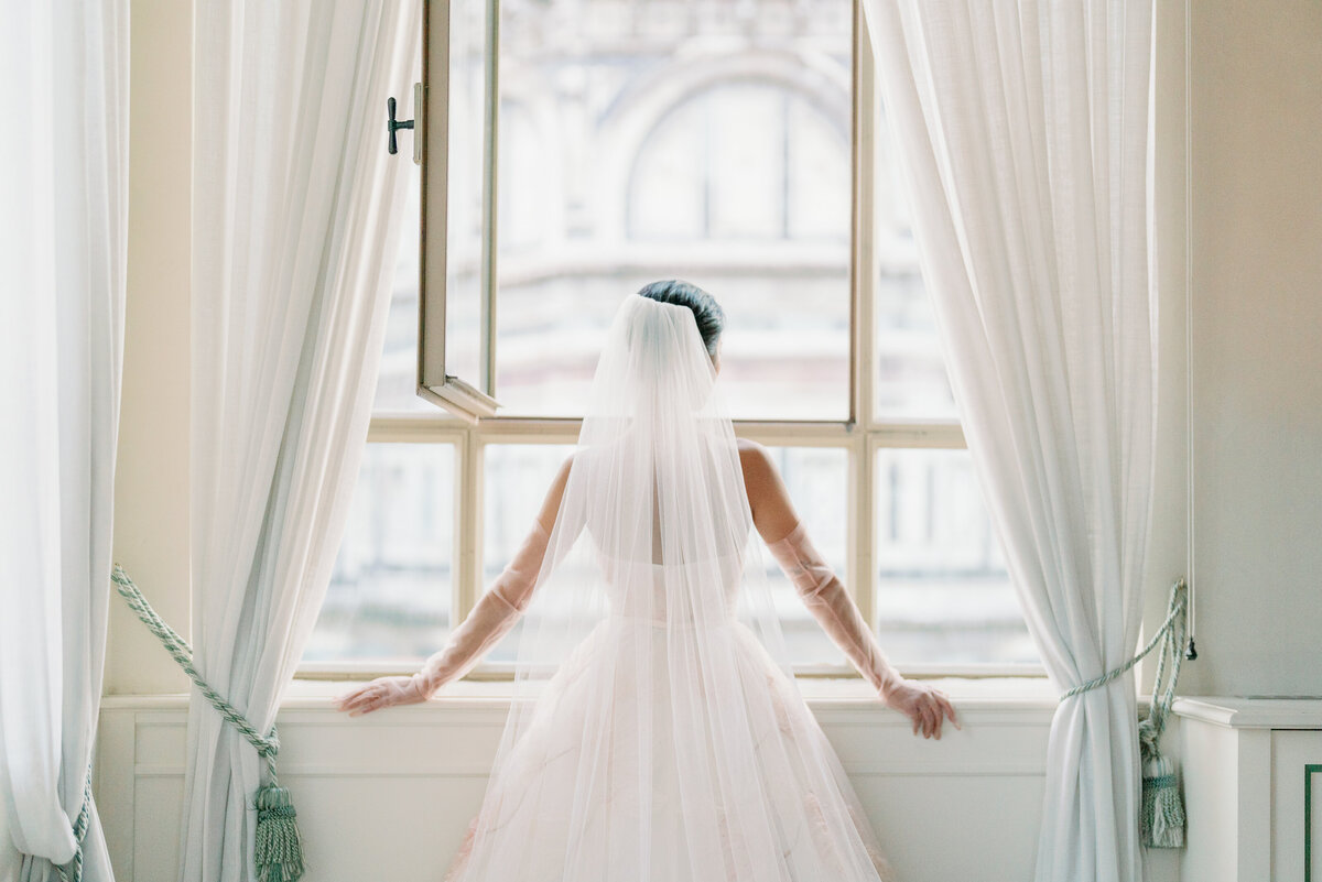 a bride with her back to the camera looking out at a window which has a view of the duomo in florence italy