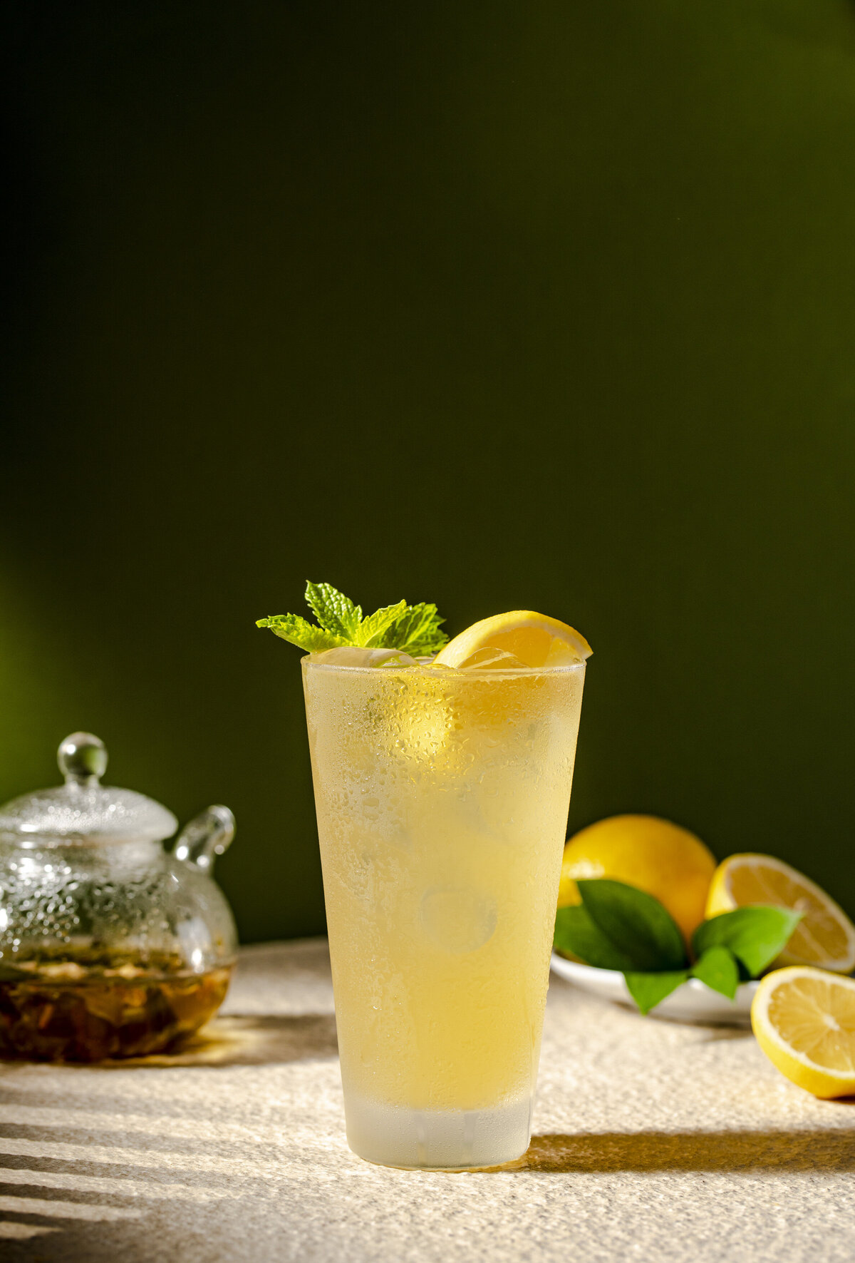 A tall glass of lemonade with mint on top.