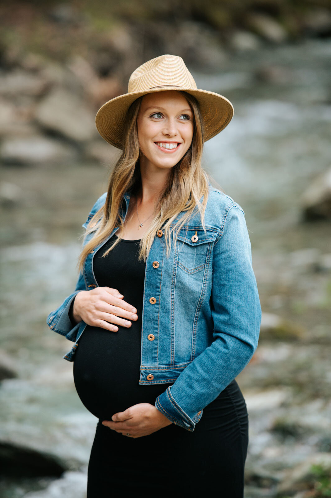 maternity pregnant woman with hat and denim jacket in vermont river