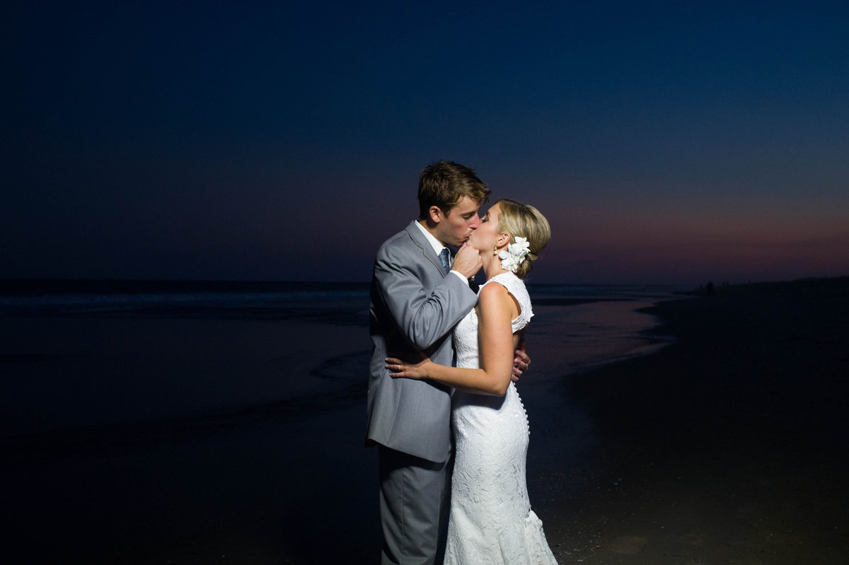 sunset on beach with bride and groom kissing