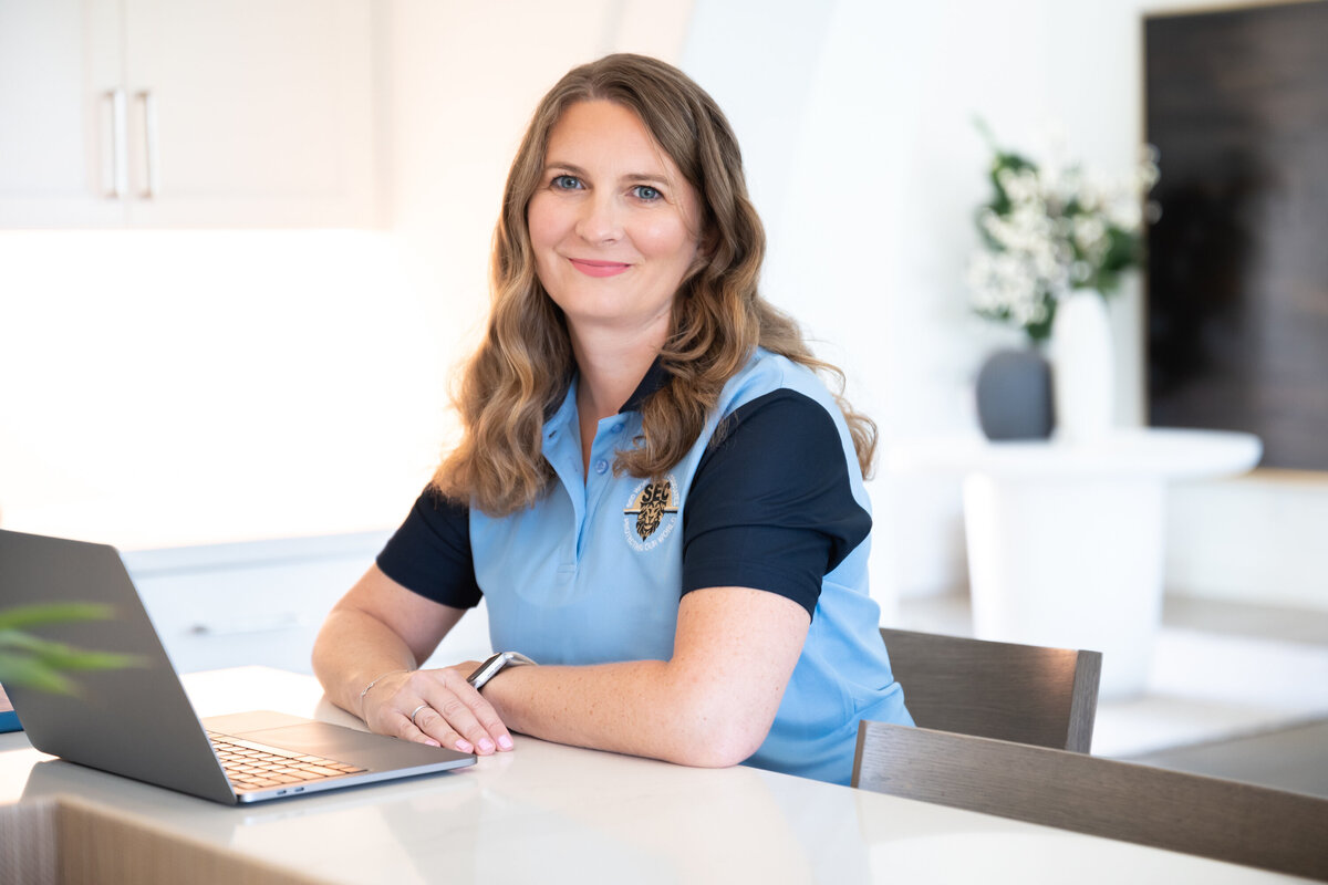 A professional image of a woman working in front of a laptop smailing to the camera