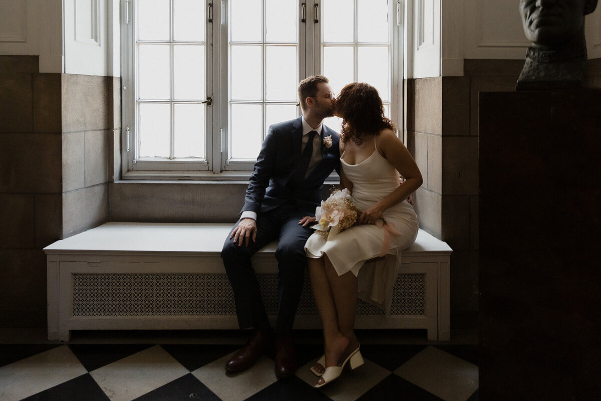 Just Married photo session couple sits in window sill at International Museum of Surgical Science and kisses