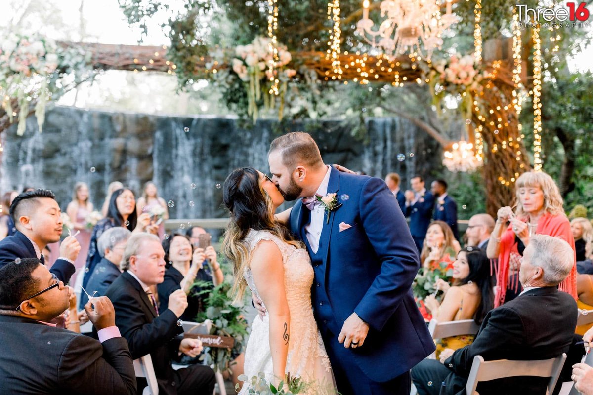Groom kisses his Bride at the end of the aisle walkway