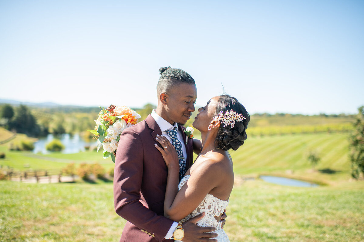 Young black couple on wedding day huggingat Stone Tower winery in  Virginia with greenery in backgroun