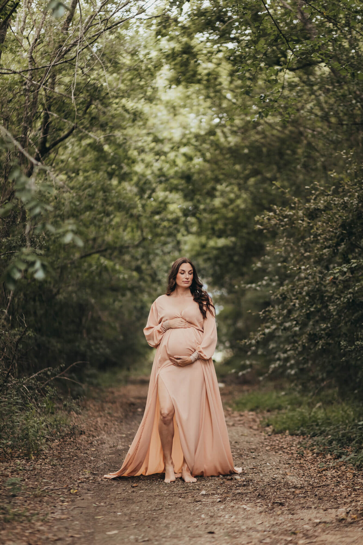mom's dress blows in the wind for her maternity session, wearing a coral maternity gown.
