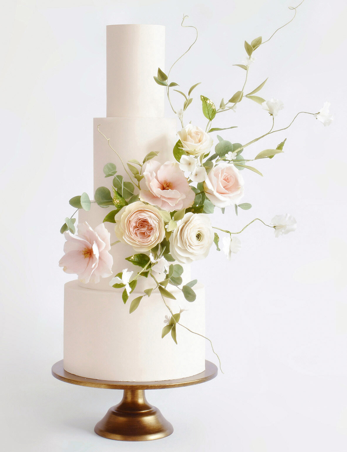 Pretty four tiered wedding cake with pristine icing and wild sugar flowers and foliage