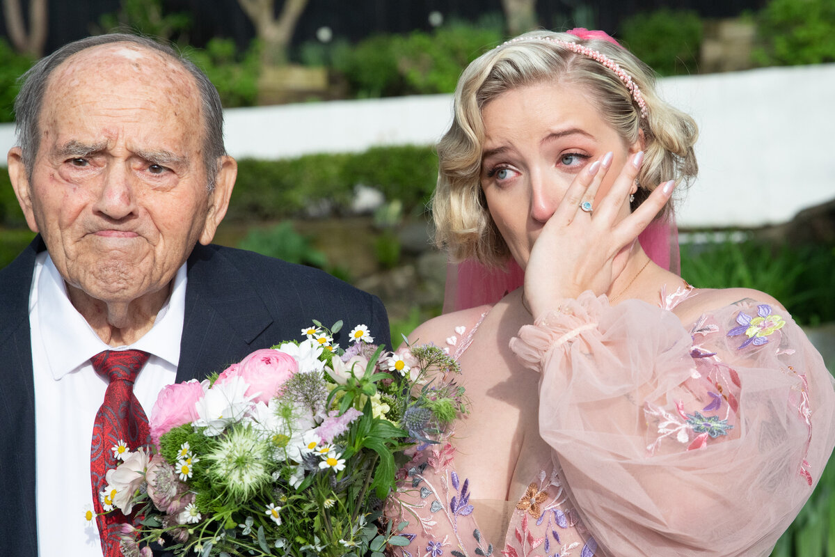 Bride in a oink dress wipes away tears next to her crying grandfather Swan Club Long Island wedding photographer Milestone Images