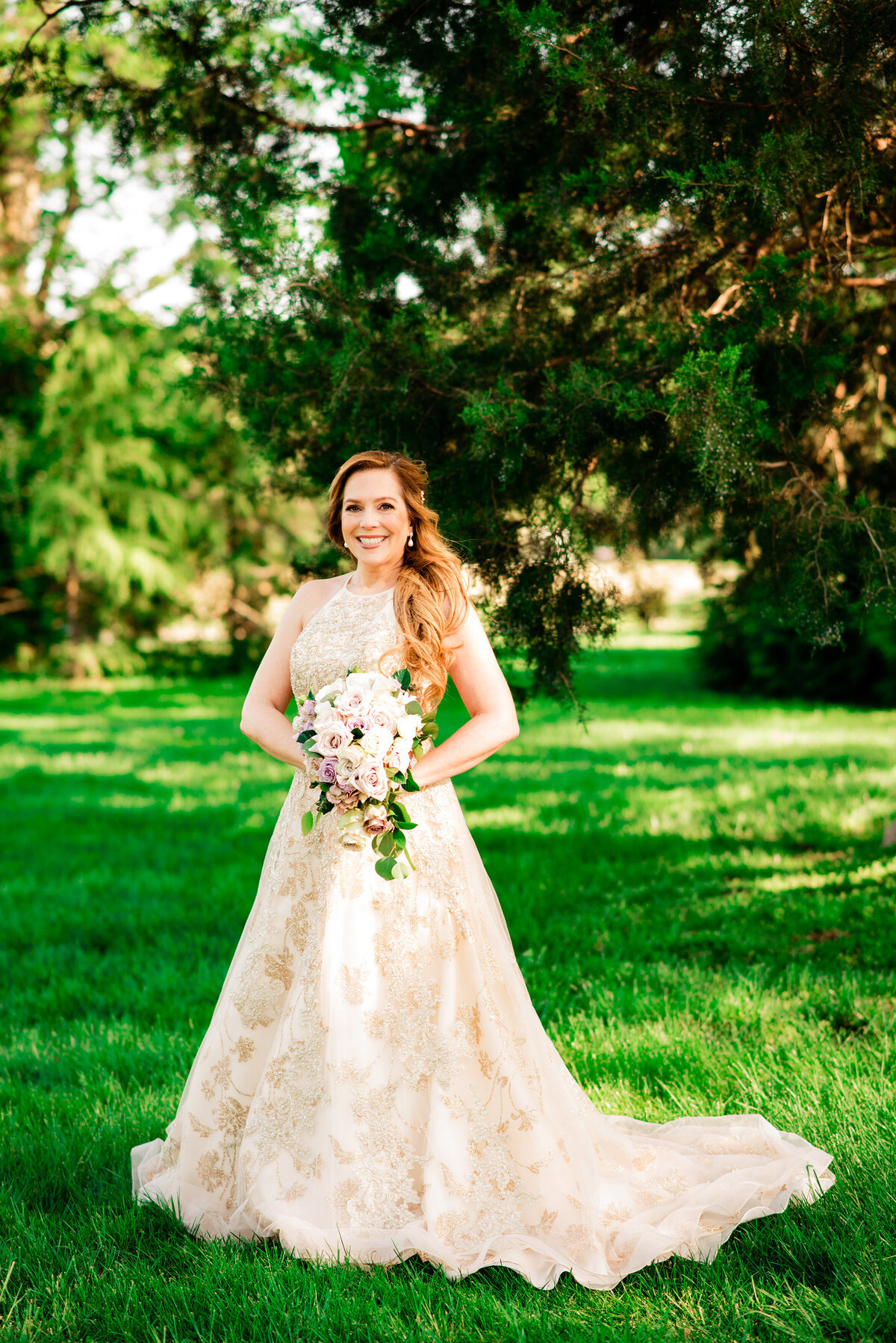 Bride wearing a golden colored wedding dress outside holding bouquet