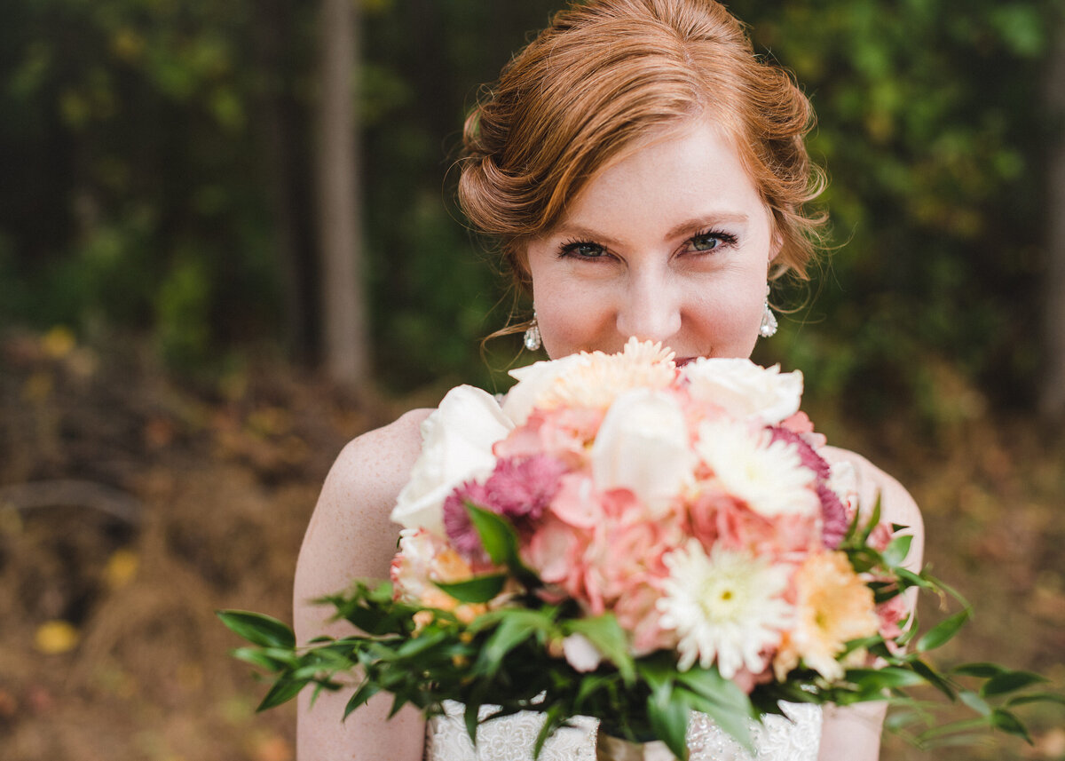 bride smiling and looking over flowers with half face hidden