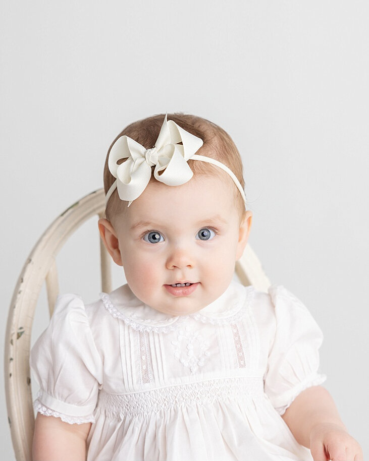 9month baby girl photographed on a white studio backdrop wearing a feltman brothers  heirloom outfit