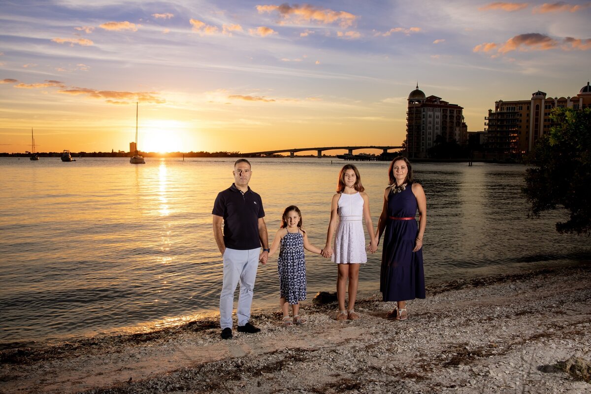 A professional family photo taken at Bayfront Park in Sarasota with the Ringling bridge and Sarasota in the background.