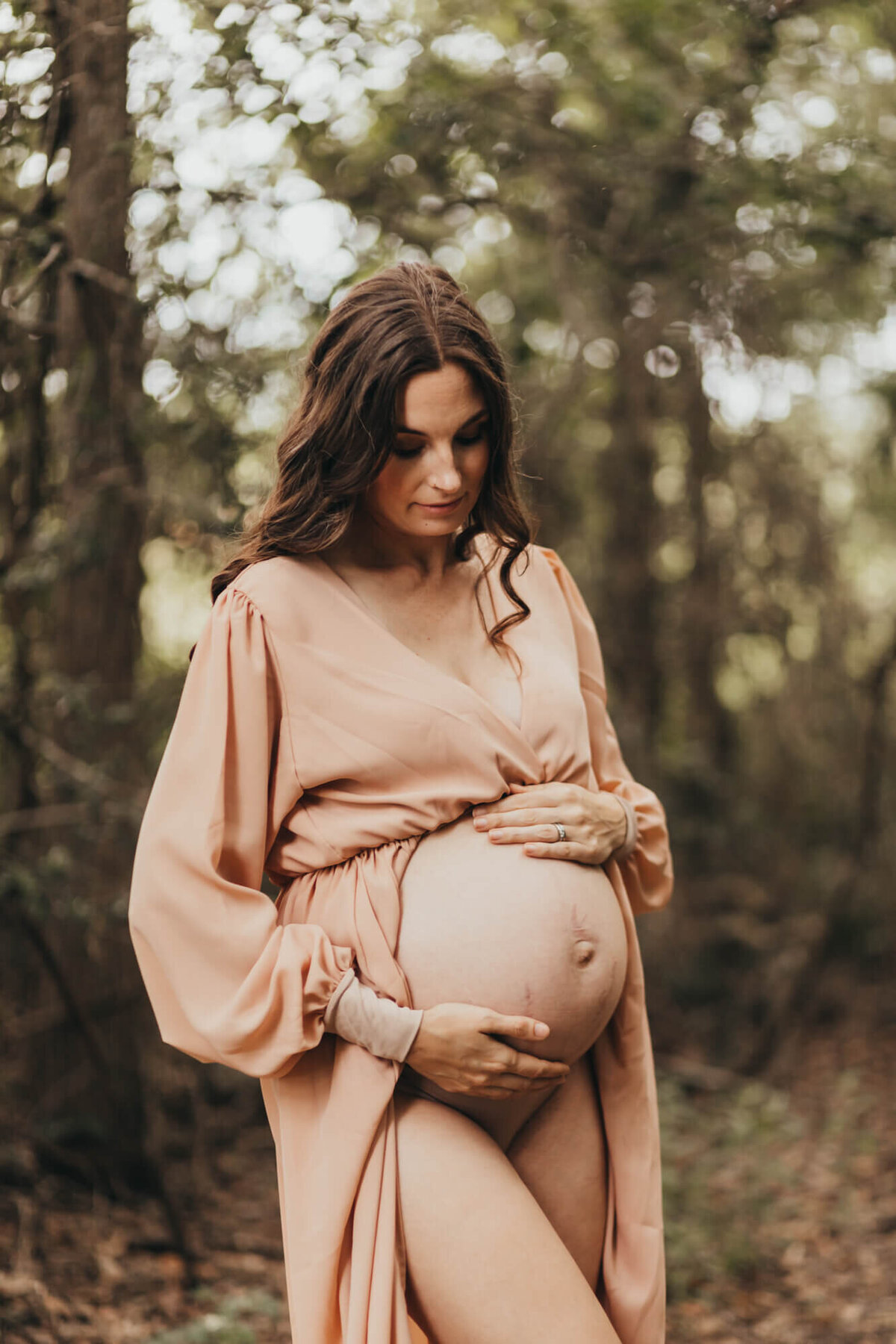 mother admires her belly with her stretch marks showing for her maternity session.