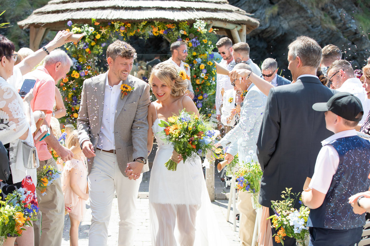 Walking down the aisle at sunny summer wedding in Tunnels Beaches Devon