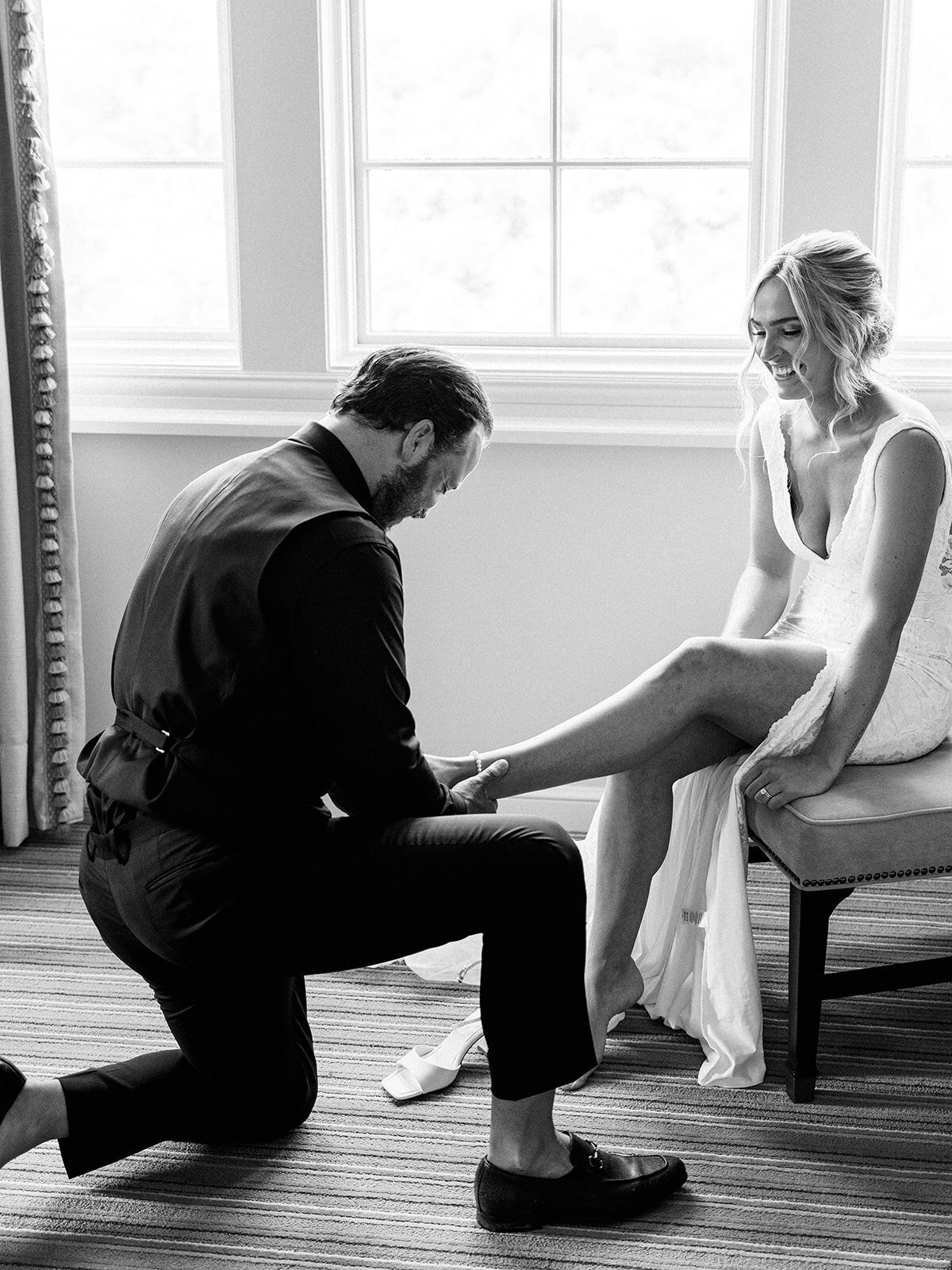 Groom helps his bride put on her shoes