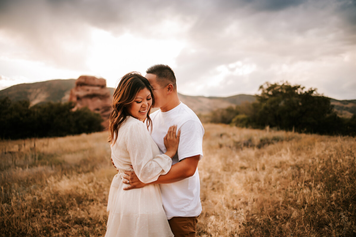 colorado couple embrace in wheat field in thornton colorado for engagement photos
