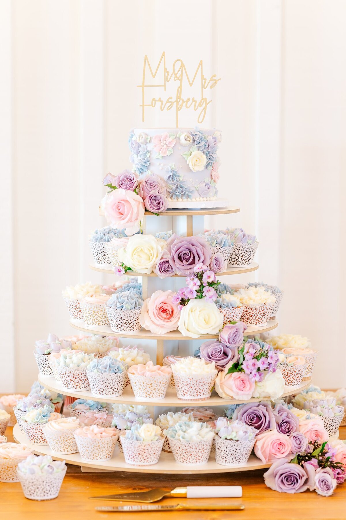 Elaborate lavender and blush pink themed wedding cake and cupcake display