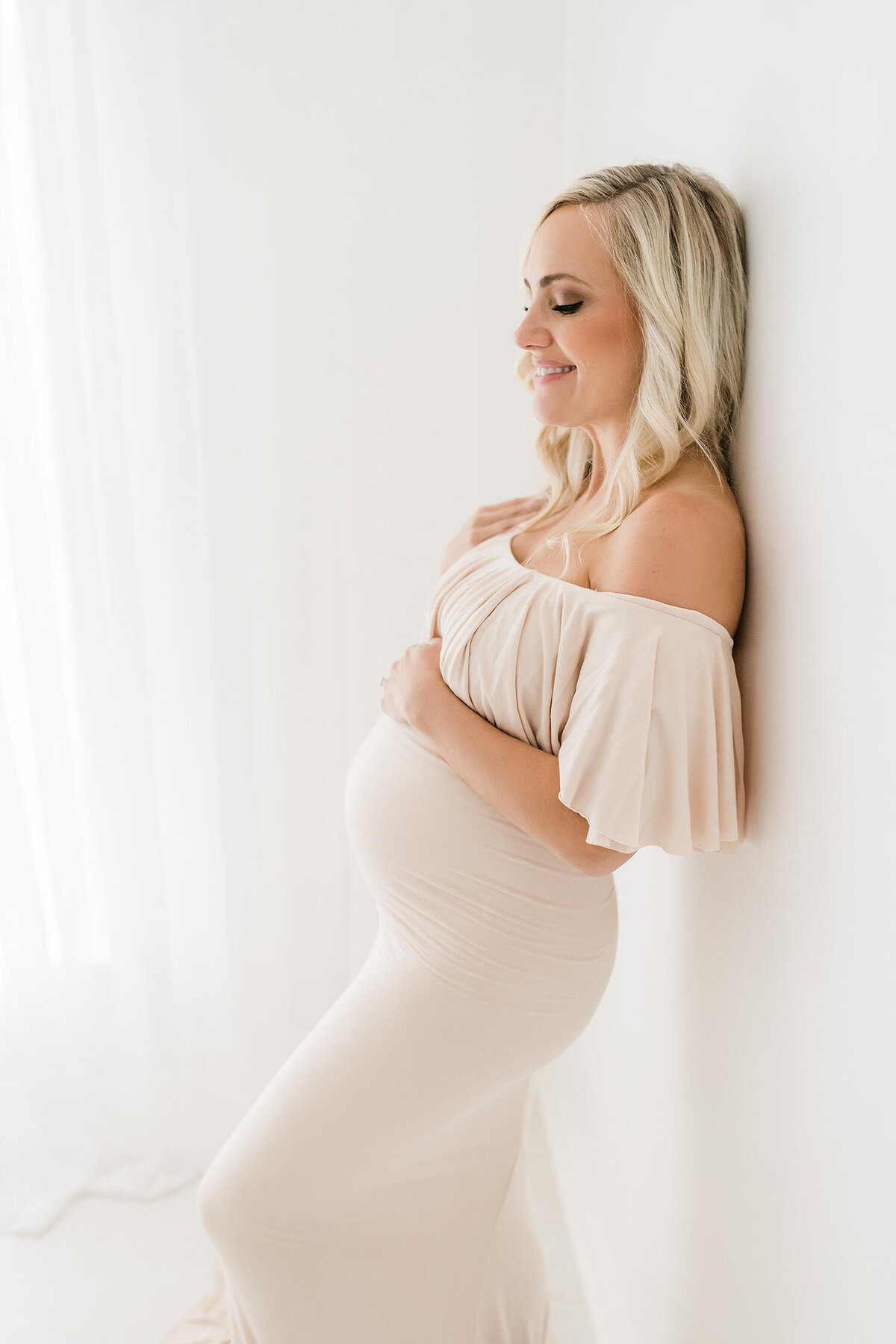 pregnant woman leaning against white wall