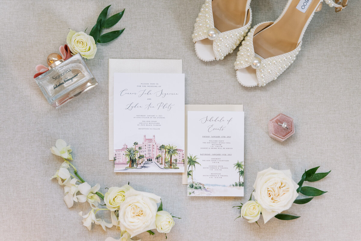 white invitation, bridal shoes, and flowers