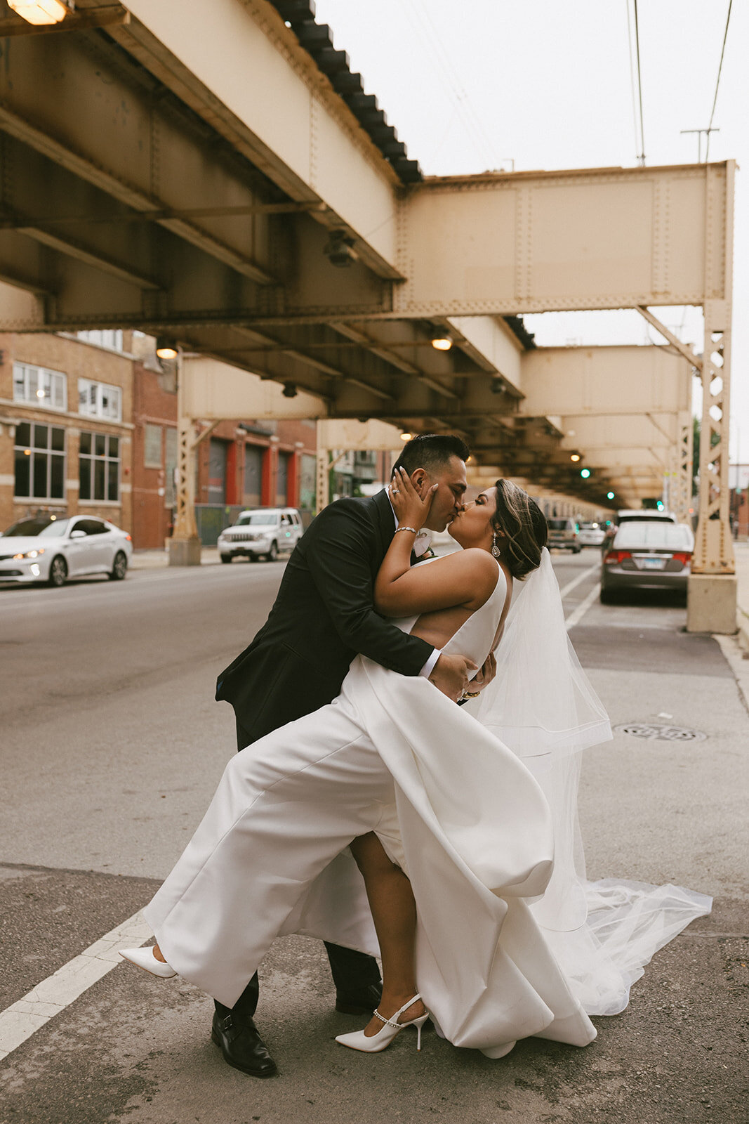 Groom dips the bride and kisses her on the streets of downtown Chicago.