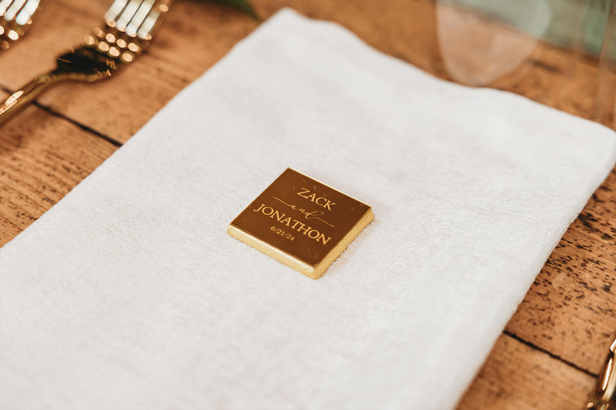 Linen napkins resting on wood table with custom gold favors.