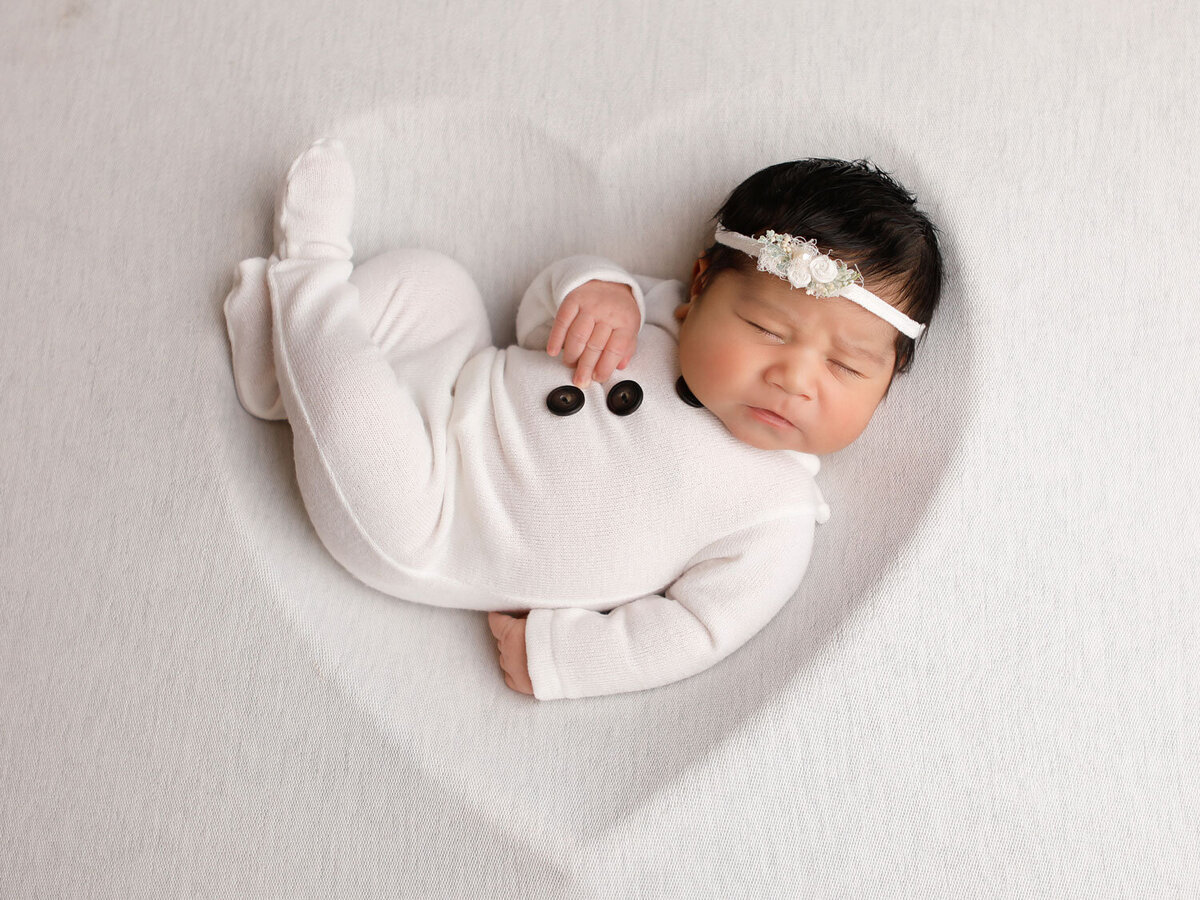 six-days-old-newborn-girl-sleeping-in-a-wooden-heart-prop-for-her-newborn-photoshoot