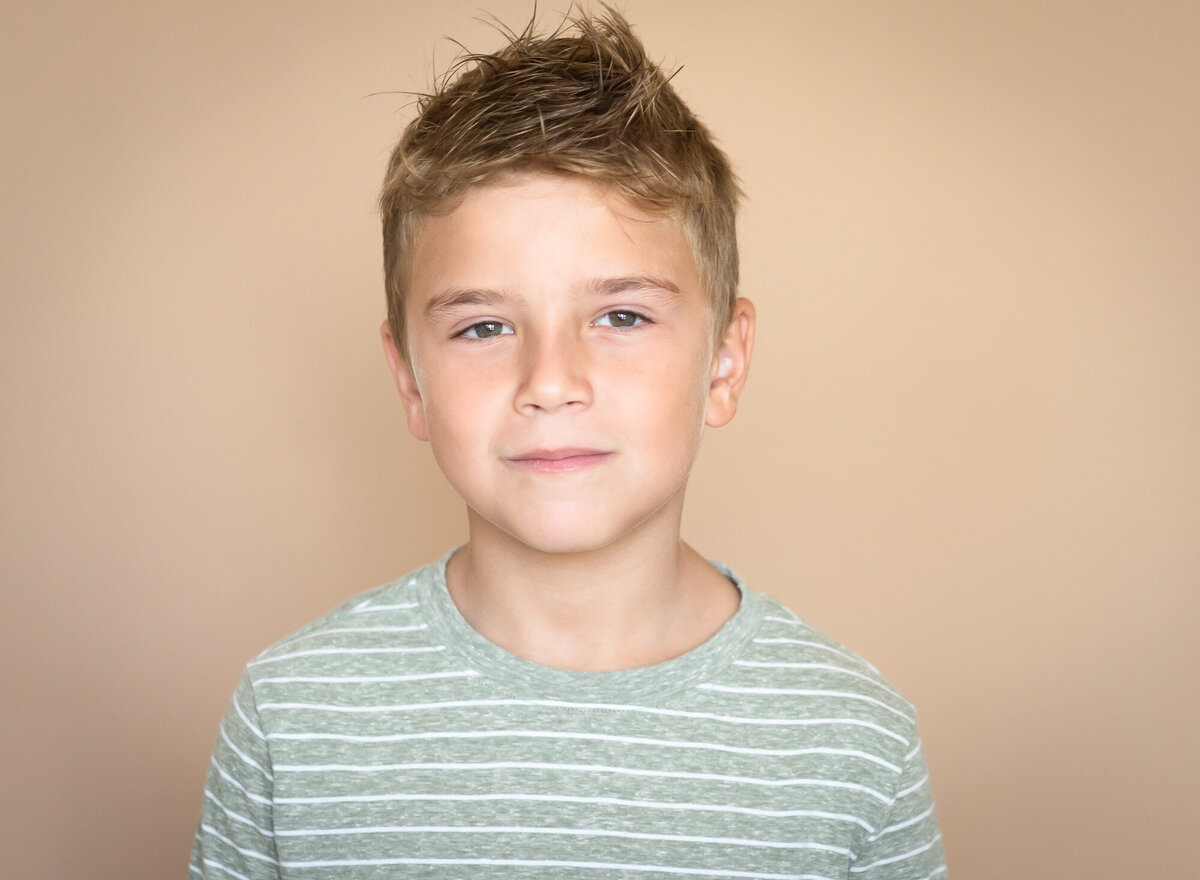 serious face on a young boy  studio portrait with tan background